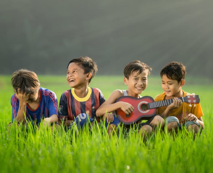 young boys giggling as one plays ukulele