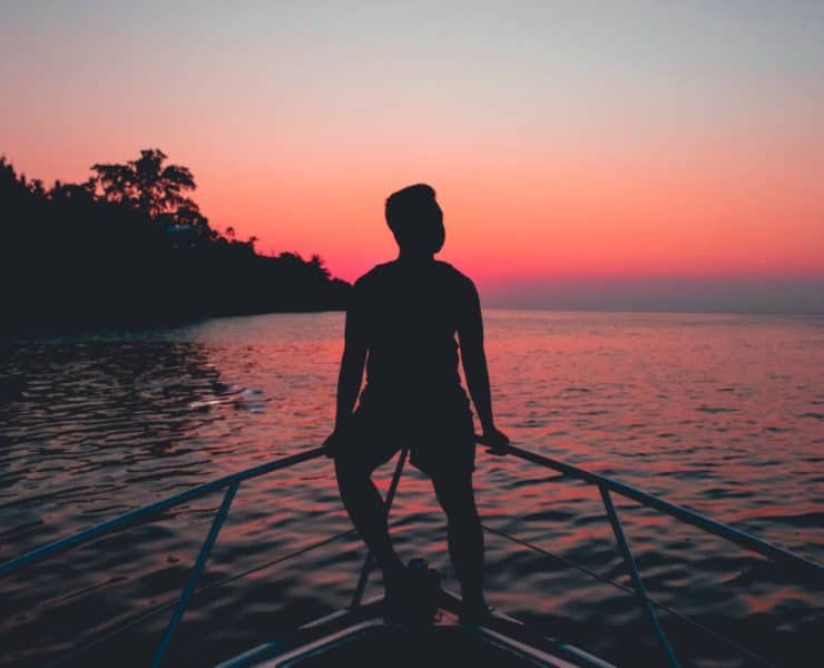 silhouette of man on boat enjoying sunset