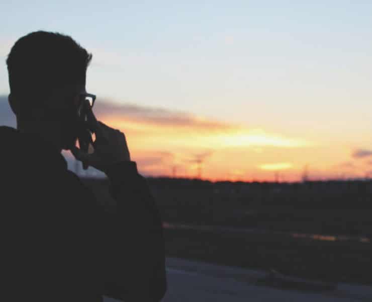 Man on cellphone watching sunset