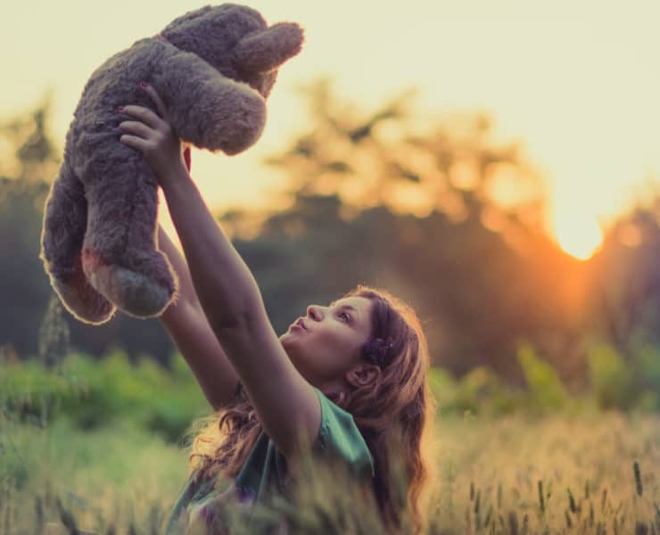 Girl holding teddy bear in the air