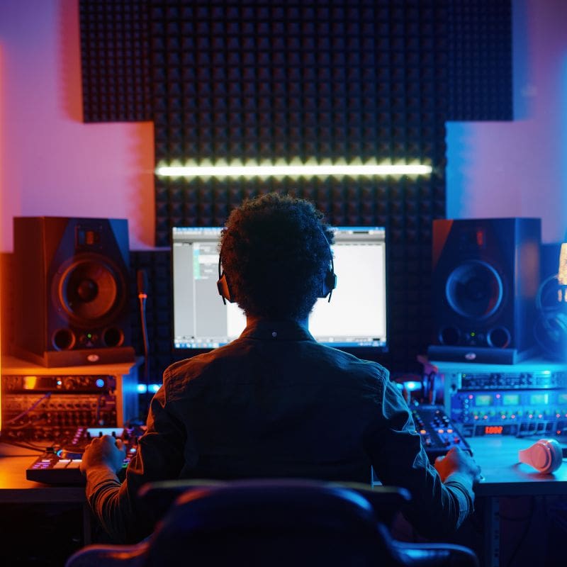 Music creator working in a professional audio production studio mixing background music.
