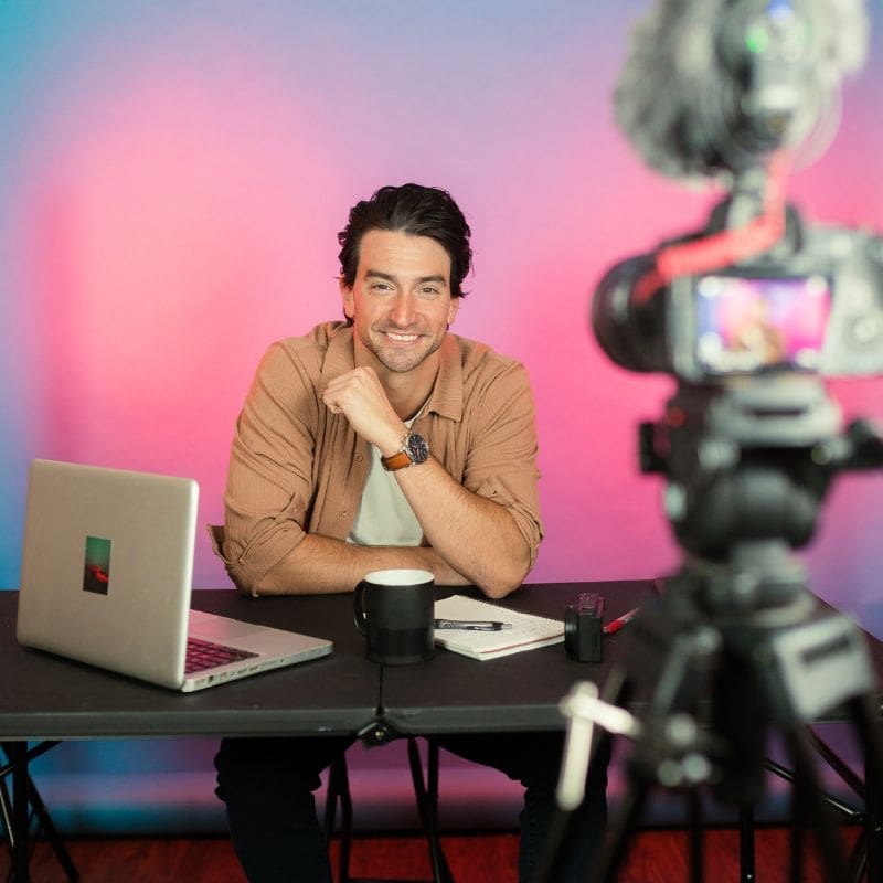 YouTube content creator recording a video with camera and laptop, using royalty free background music for online projects.