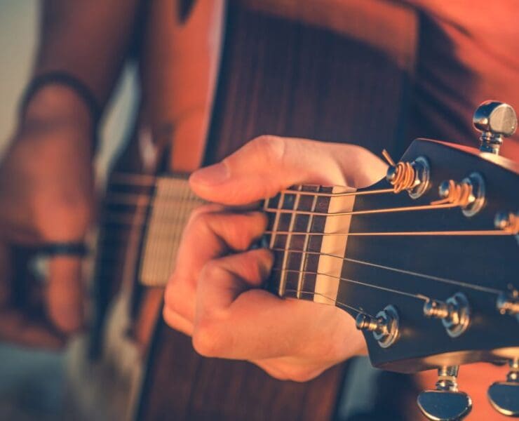 Smiling person meditating beside a calm lake at sunrise with soft warm colours, used as artwork for an acoustic track titled Easygoing Moments.